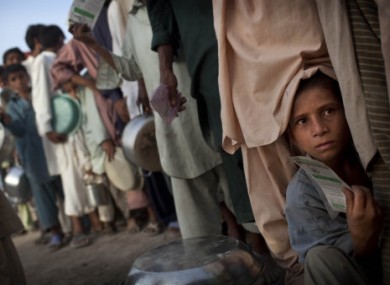 A young Pakistani boy displaced by flooding holds his ration card as he tries to push as they line up for hot meal