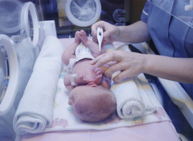 Midwife taking temperature of new born baby lying in Phototherapy machine. Library photo, posed by models.