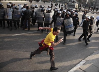 A demonstrator runs past a line of riot police in Cairo, Egypt, on Tuesday, 25 January 2011.