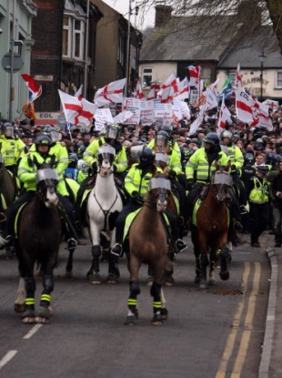 A group of English Defence League members are watched by mounted police as they march through Luton today.