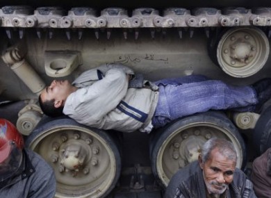 Protester sleep under - and on - tanks to prevent them moving as they occupy Tahrir Square, Cairo.