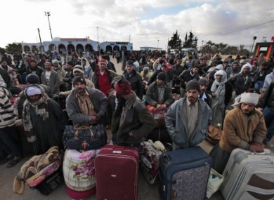 Egyptians, who used to work in Libya, wait for buses to take them further inland today after fleeing Libya.