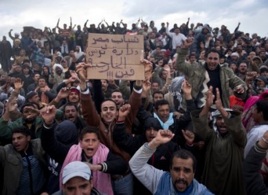 Crowds of Egyptian workers who crossed the Tunisian border out of Libya react to a photographer today.