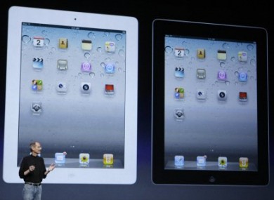 Apple CEO Steve Jobs stands under images of the iPad 2 at an Apple event in San Francisco this evening.