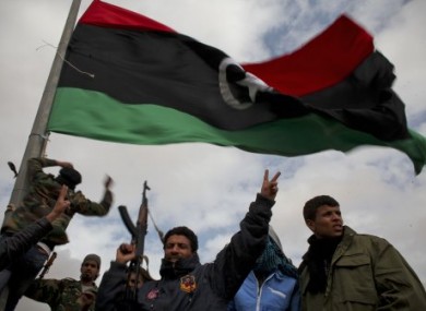 Libyan volunteers gesture as they raise a pre Gadhafi flag on the outskirts of the eastern town of Ras Lanouf, Libya, yesterday.