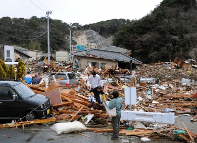Residents walk through the rubble of houses collapsed by the earthquake in Iwaki, Fukushima state