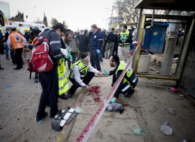 Israel rescue workers and paramedics clean a pool of blood at a bus stop in Jerusalem following this lunchtime's explosion.