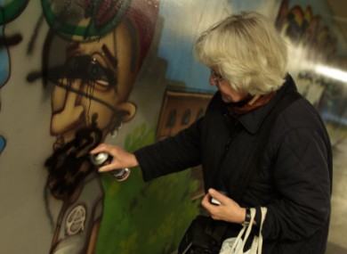 Irmela Mensah-Schramm sprays over a swastika sign in Berlin.