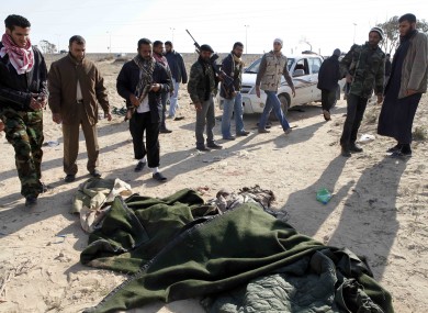 Libyan rebels stand near covered bodies in the city of Ajdabiya yesterday, after regaining control of the town.