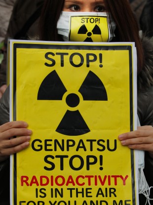 A protester holds a placard during an antinuclear rally in Tokyo earlier today, as staff were once again evacuated from the Fukushima I power plant.