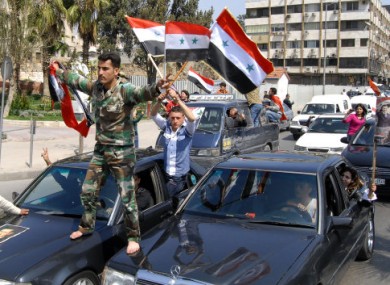 A Syrian soldier waves Syrian flags during a pro-Assad demonstration in Damascus yesterday.