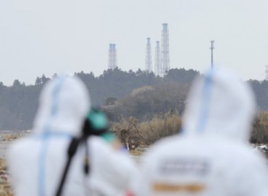 The exhaust stacks of the Fukushima Daiichi plant tower above woodland.