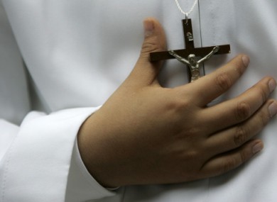 A boy holds his crucifix before receiving first communion.