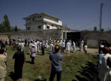 Local people and media gather outside the wall of the compound and house where bin Laden was killed.