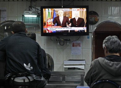 Two Portuguese men sit in a restaurant watching caretaker prime minister Jose Socrates announce their country's bailout.