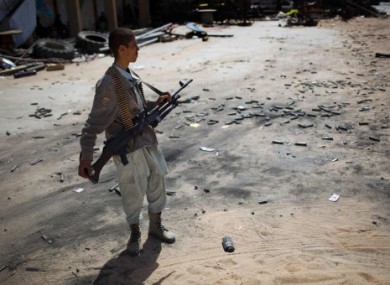A rebel fighter stands amid fired munitions at the front line between the rebels and Gaddafi's forces 25km west of Misrata today.