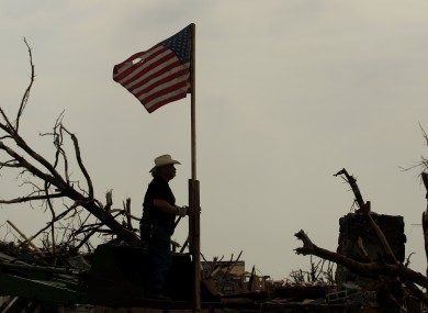One man raises the American flag as he helps clean up the devastation.