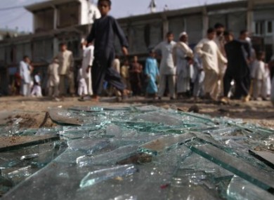 Afghans walk past the debris at the site of an explosion in Laghman province today.