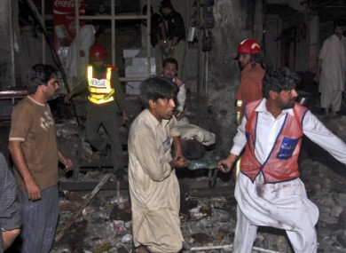 Pakistani rescue workers carry away a wounded man from the site of an explosion in Peshawar, Pakistan, early this morning.