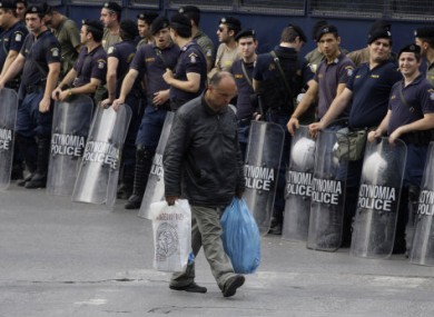 A man passes next to riot police officers that block the way to the Greek Parliament in central Athens on 15 June, 2011.