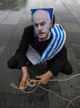 A protester with a mask of prime minister George Papandreou prepares himself as a marionettes prior to a protest in Athens.
