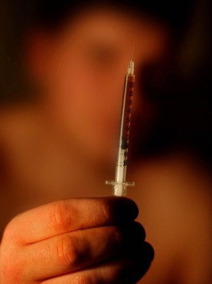 A drug addict holds up a heroin needle (File photo)