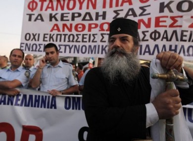 A priest stands in front of demonstrating police officers outside the Greek Parliament in Athens yesterday.