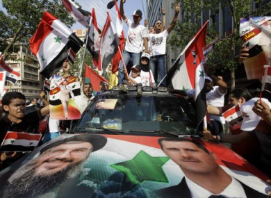 Syrian protesters carry flags and shout pro-government slogans during a rally outside the Syrian embassy in Beirut on 24 July 2011.