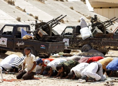 Rebel fighters pray at a last rebel checkpoint some 80 kilometers east from rebel-held Misrata