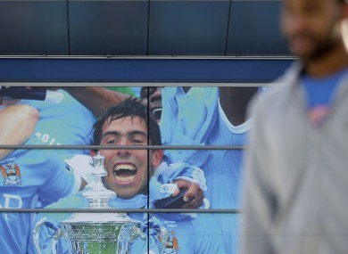 A fan passes a mural outside Manchester City's Etihad Stadium.