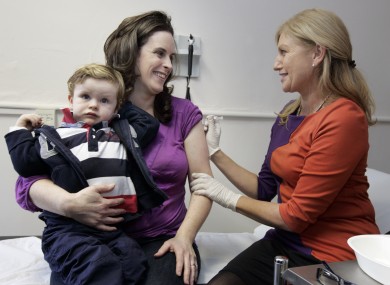 Nurse Brid Ryan O'Malley, right, gives pregnant mum Sally Downing from Clonsilla a vaccination againt seasonal flu as two-year-old son Cian O'Leary looks on today in Dublin.