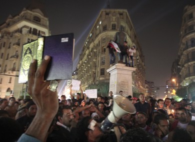 An Egyptian lifts the Muslim holy book, the Quran, as others light candles at Talat Harb square in downtown Cairo to mourn last week's attacks.