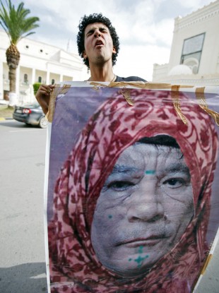 A Libyan man reacts as he holds a photo of Muammar Gaddafi, manipulated to show the leader dressed as a woman, in Tripoli today.