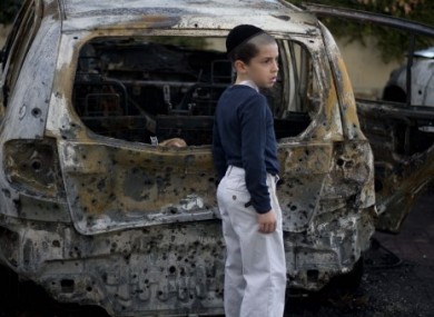 A boy stands next to a burned cars following Saturday night's rocket attacks from the Gaza Strip, in Ashdod, southern Israel, early Sunday, 30 October.