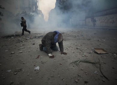 A protester overcome with tear gas inhalation kneels in the middle of the street during clashes with the Egyptian riot police today.