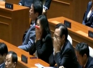 Politicians cover their mouths after tear gas is let off in the South Korean parliament