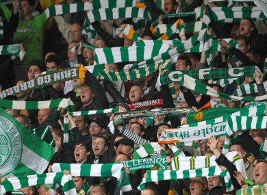 Celtic supporters hold their scarves in the air.