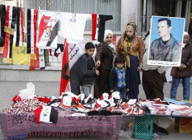 A Syrian family looks at hats, scarves and shirts with Syrian flags and Assad portraits in Damascus yesterday.