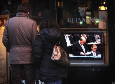 A couple stop to watch a television outside a pub in Dublin as Finance Minister Michael Noonan delivers the budget