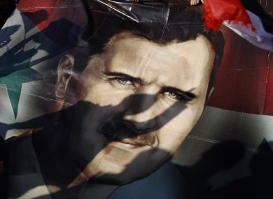Shadows of Syrians are reflected on a giant poster showing President Bashar Assad