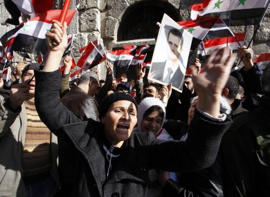 Mourners wave Syrian flags and a photo of President Bashar Assad as they chant slogans at a mass funeral for 44 people killed in suicide bombings earlier this week.