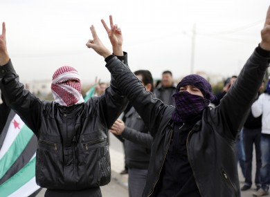 Masked Syrian refugees make victory signs at a protest in front of the Syrian embassy while chanting slogans against President Bashar Assad in Amman, Jordan