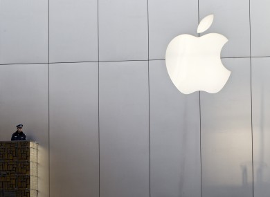 A police officer stands watch near a Apple's logo after they sealed off the area of its store in Beijing today. The store was egged by angry customers when it didn't open on time.