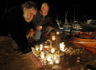 Gus Dempsey (left) and George Webb light candles at a memorial in Union Hall for the five missing men off the coast.