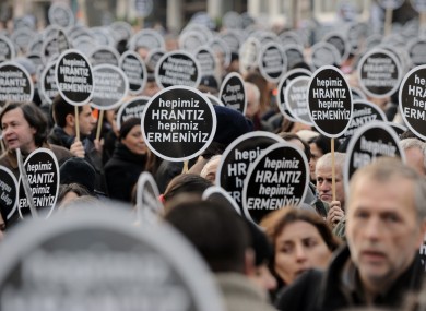 Protesters hold signs reading