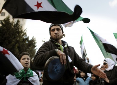 Anti-Syrian regime protesters carry revolutionary flags while performing a traditional dance during a protest outside the Arab League headquarters in Cairo, Egypt, yesterday