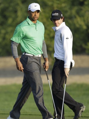 Tiger Woods and Rory McIlroy examine their putts on the 10th green in Abu Dhabi this morning.