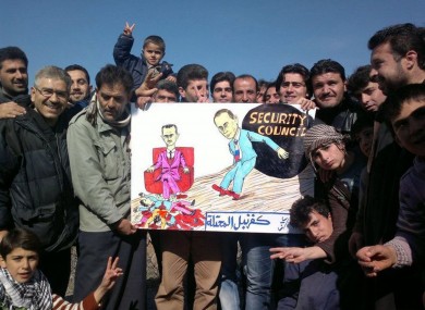 Anti-Assad rotesters pose with a banner depicting Assad with Vladimir Putin and bearing the words