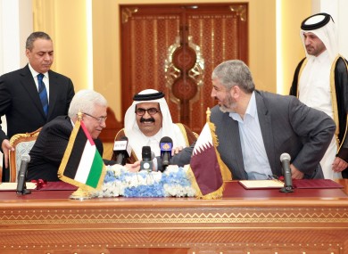 Palestinian President Mahmoud Abbas, left, shakes hands with Khaled Mashaal, right, as the Emir of Qatar looks on following the 6 Feb deal signing.
