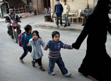 A woman walks with children in Kafar Taharim, north Syria on Saturday. The town is controlled by the opposition Free Syrian Army.